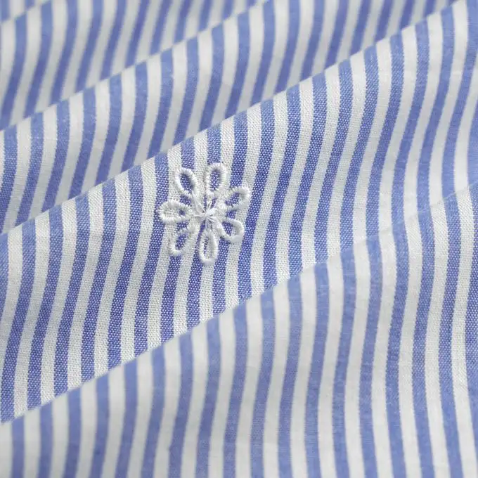 Tessuto a righe blu e bianco ricamato margherita